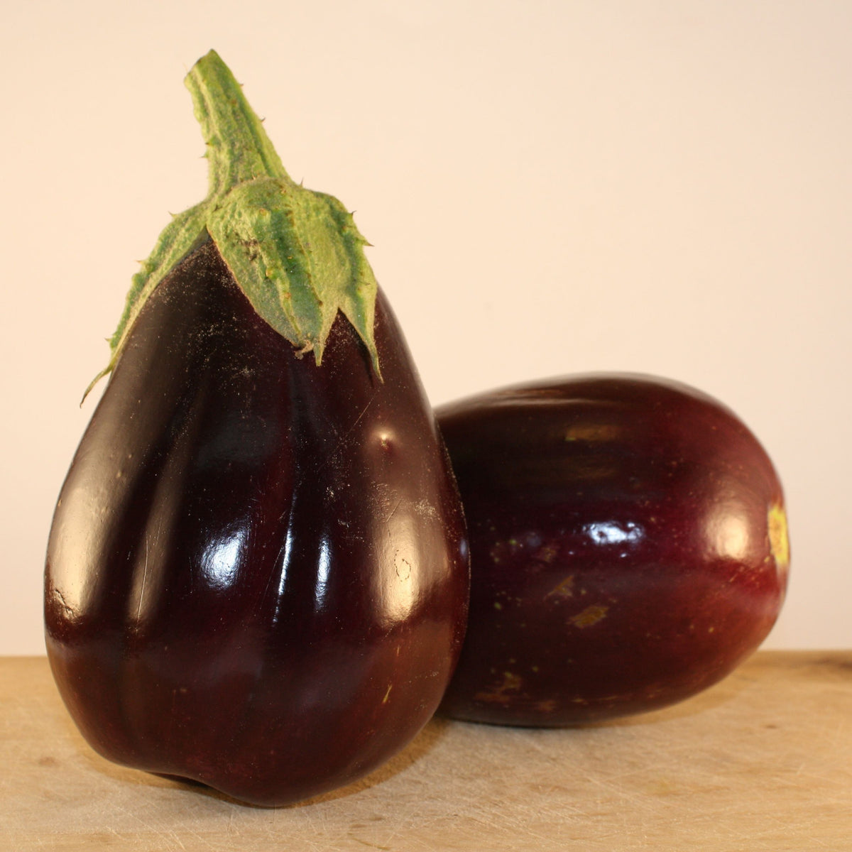 Deux Aubergines Black Beauty de Tourne-Sol sur une table en bois.